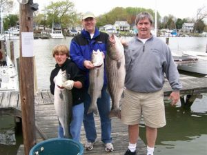 Photo of two adults and a child holding fish